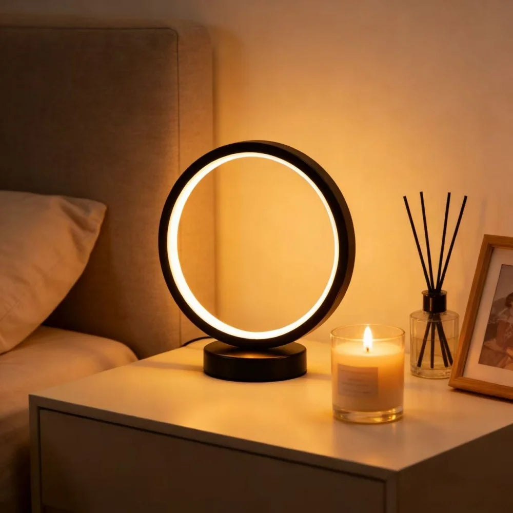 Glow & Drift Eclipse Minimalist Halo Lamp emitting a warm amber circular light on a white nightstand next to a candle