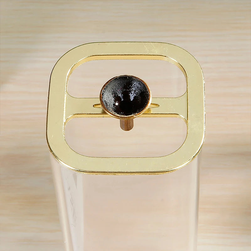 Close-up macro top view of the polished brass gold metal bracket customized for holding backflow incense cones securely over the opening of the square glass anti-ash vessel.
