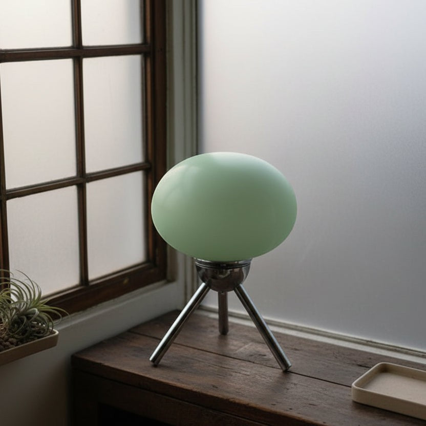 Glow & Drift Alva Bauhaus table lamp with a mint green mushroom glass shade and polished chrome tripod base on a desk.