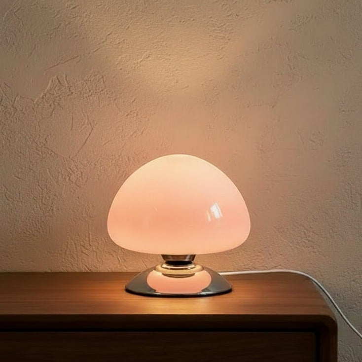 Glow & Drift Aura glass mushroom table lamp with a soft glowing dome and polished chrome base on a wooden nightstand.