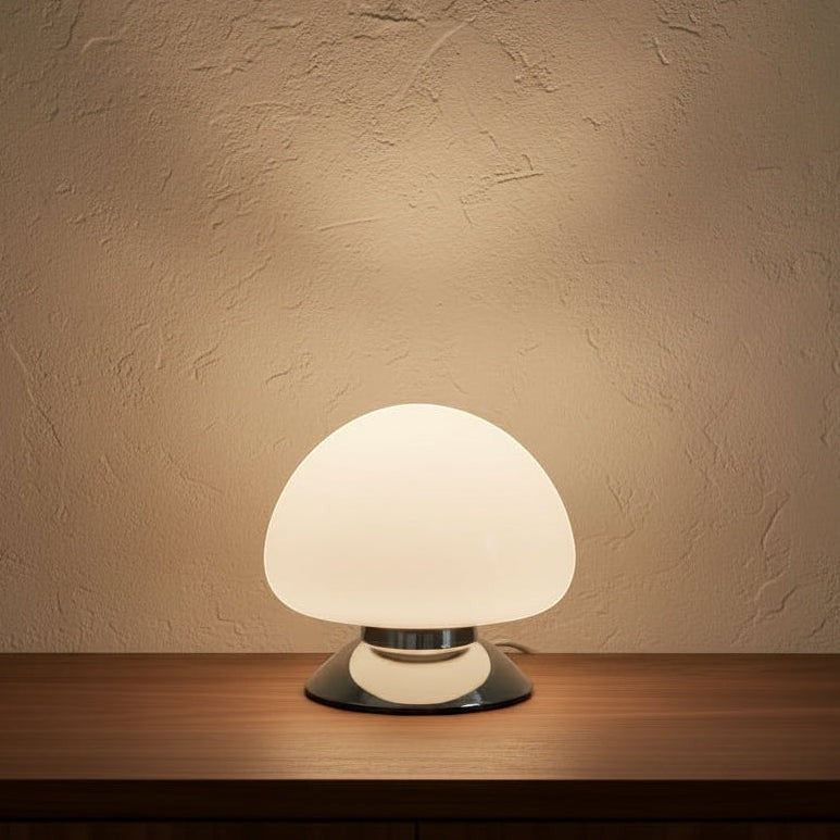 Glow & Drift Aura glass mushroom table lamp with a white dome shade and polished chrome base emitting a soft warm glow.