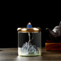 Glow & Drift Azure Peak backflow incense burner with a blue glass mountain inside a clear cylinder and gold mesh lid.