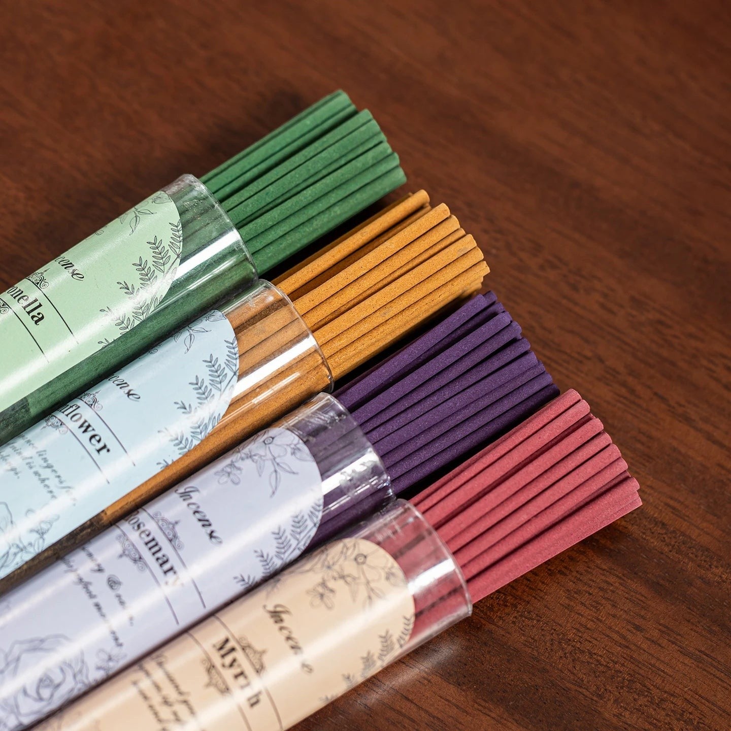 Glow & Drift botanical incense sticks in assorted colors including green, gold, purple, and red in clear tubes.