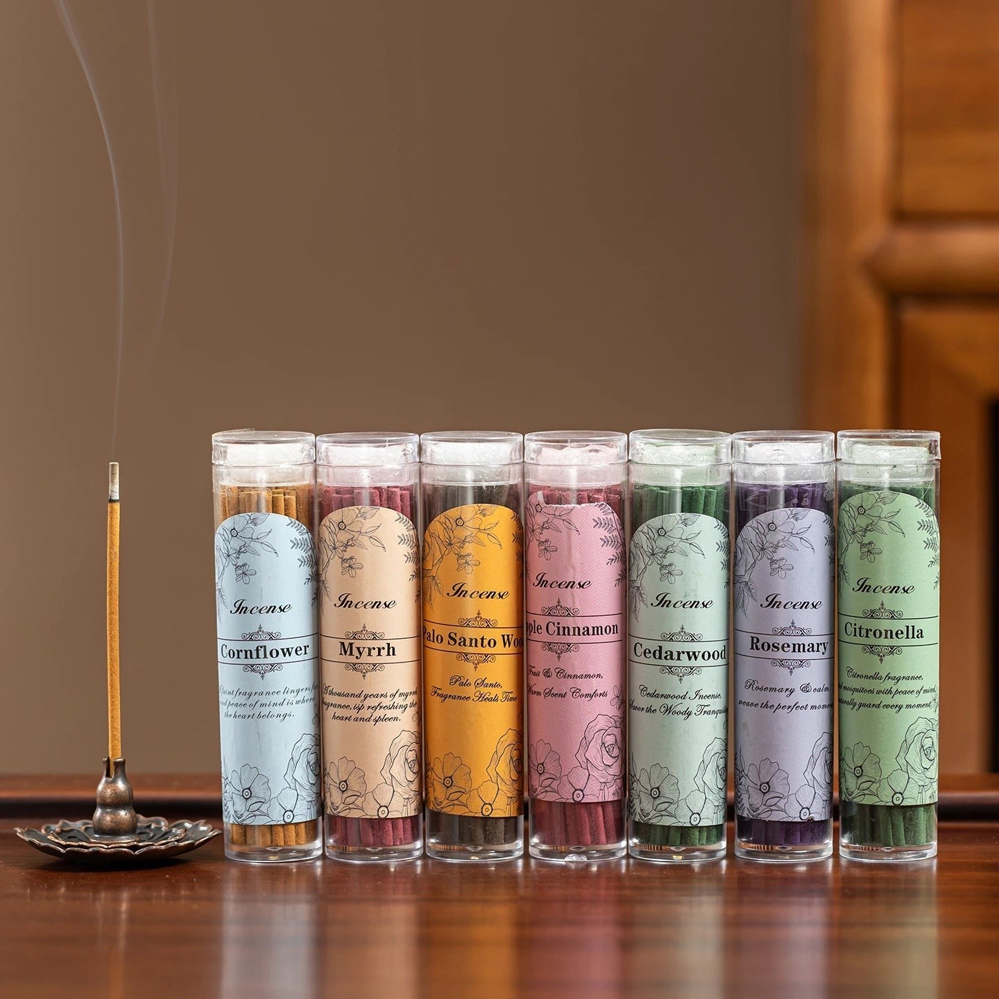 Glow & Drift botanical incense sticks in clear storage tubes with a burning stick on a metal holder