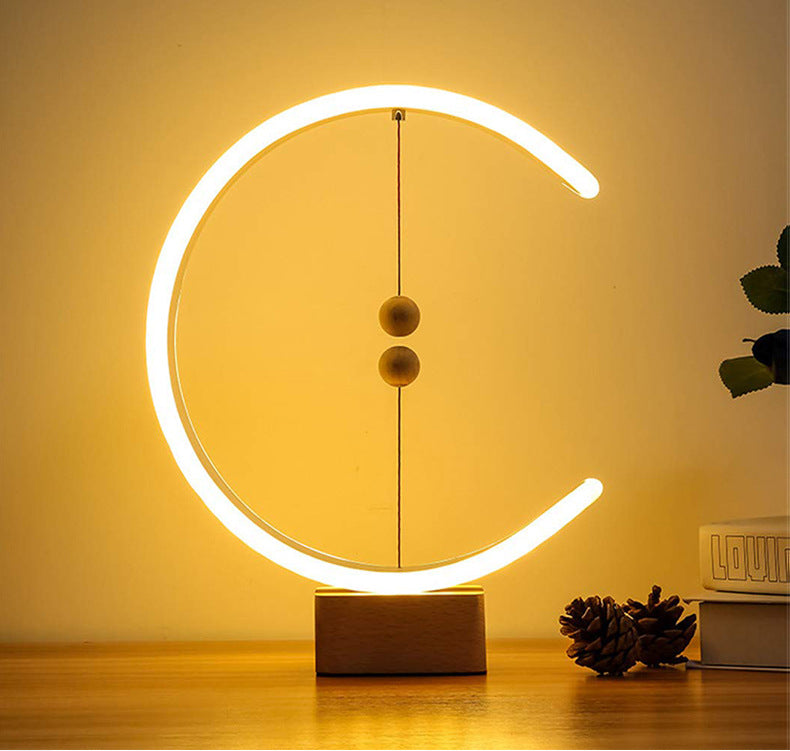 The signature Crescent Magnetic Balance Lamp by Glow & Drift, featuring an architectural C-shaped halo emitting a soft golden light, activated by two levitating magnetic spheres suspended over a premium wooden base.