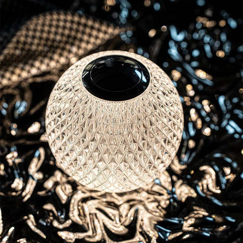 Glow & Drift crystal atmosphere lamp with a diamond-cut faceted acrylic shell and top touch sensor, glowing warmly.