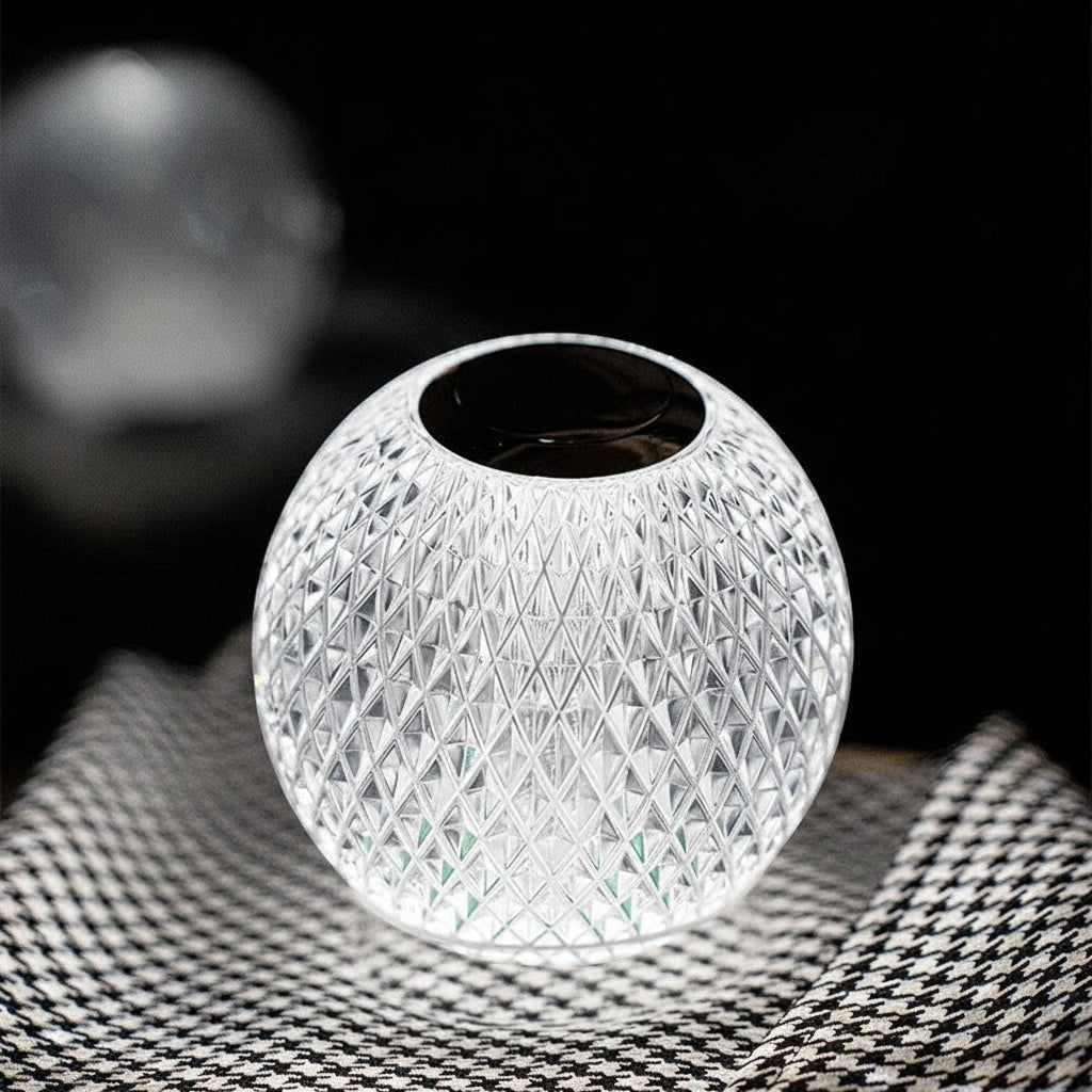Glow & Drift crystal atmosphere lamp with a faceted diamond-cut design, glowing on a houndstooth patterned surface.