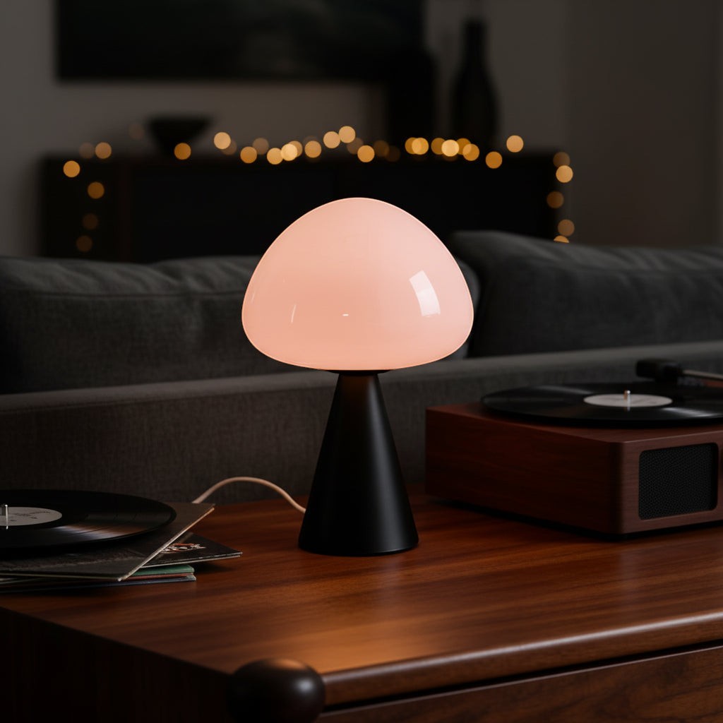 Glow & Drift Eclipse mushroom lamp with a matte black iron base and glowing glass dome on a wooden table.