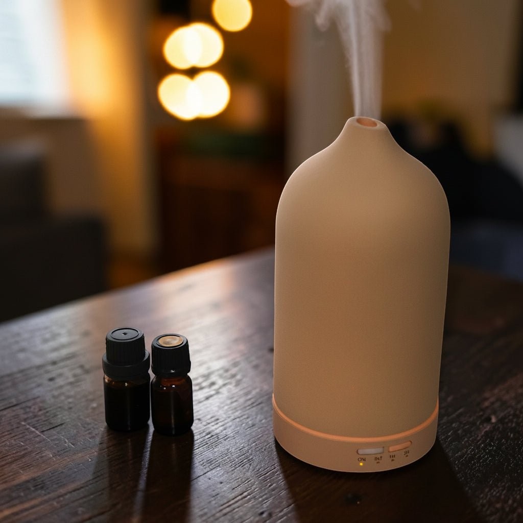 Glow & Drift minimalist frosted ceramic essential oil diffuser emitting a cool mist on a wooden table with oil vials.
