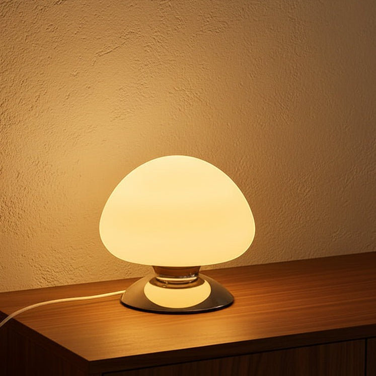 Glow & Drift Aura glass mushroom table lamp with a glowing dome and polished chrome base on a wooden surface.