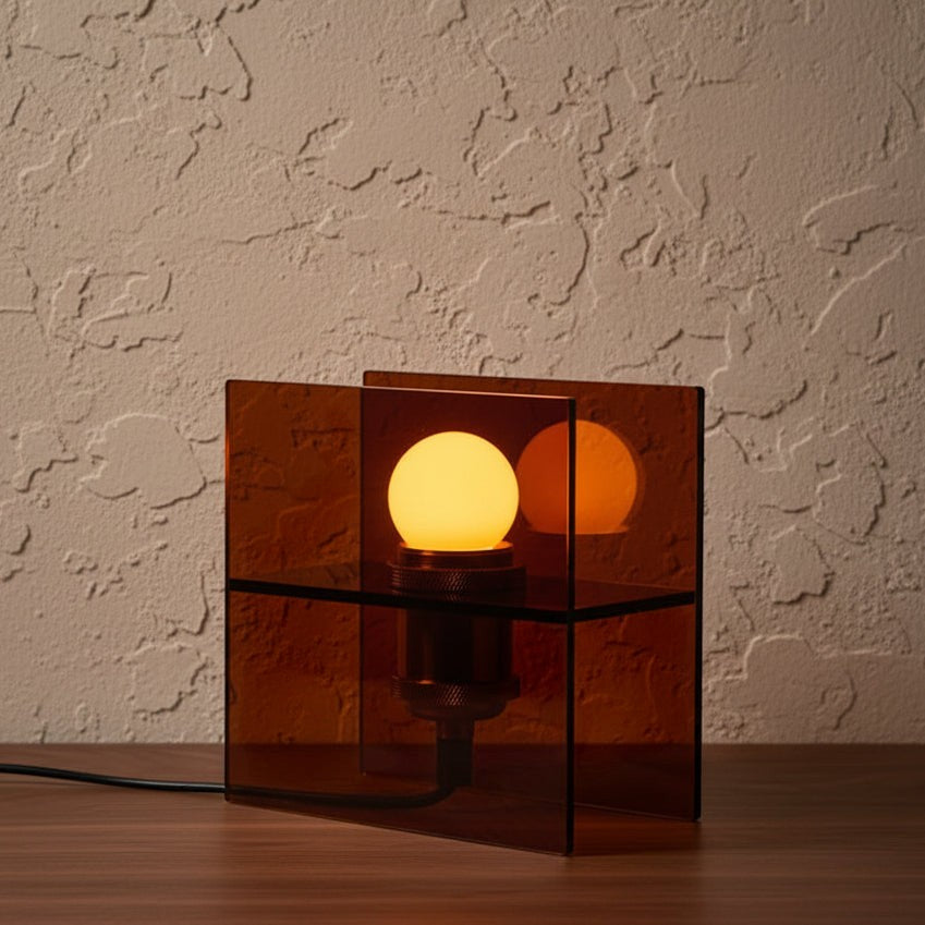 Glow & Drift Horizon geometric table lamp with amber tinted acrylic panels and a warm glowing E27 bulb on a desk.