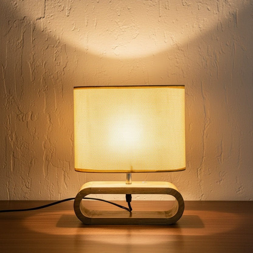 Glow & Drift Japandi wooden table lamp with an organic linen shade casting a warm, diffused glow on a textured wall.