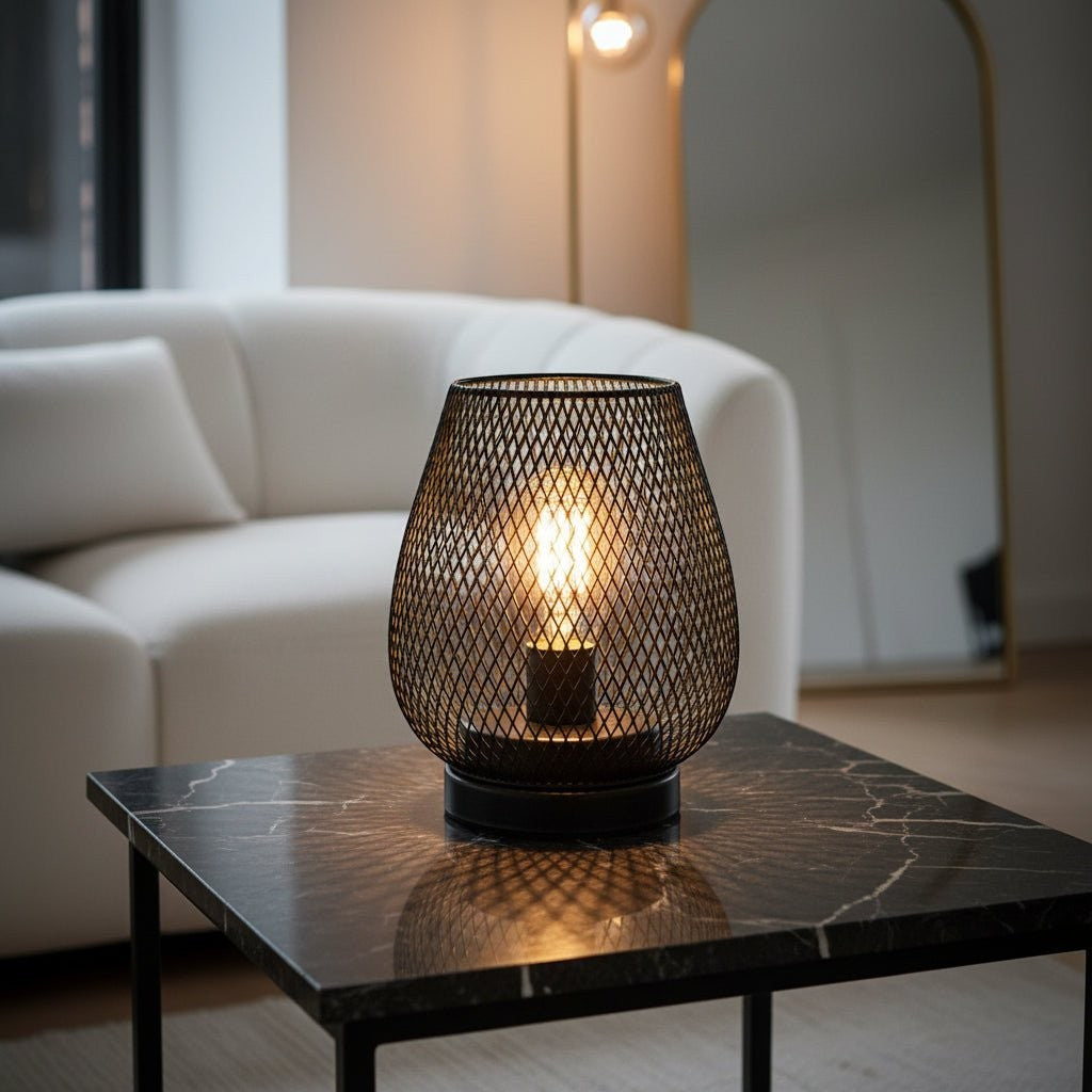 Glow & Drift Lumina Cage Retro Filament Lamp with a black iron mesh frame and warm Edison bulb on a marble table.