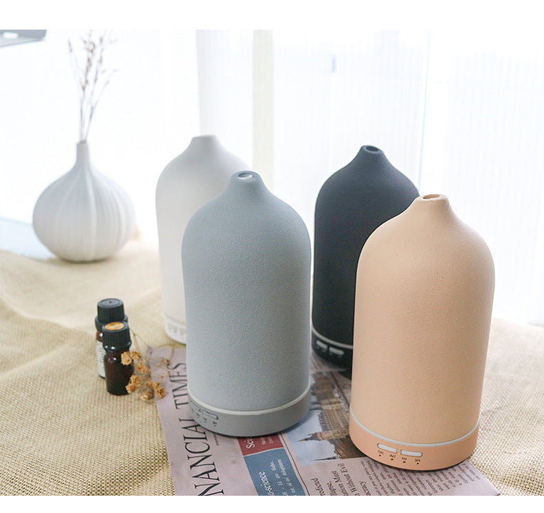 A beautiful collection of Glow and Drift Minimalist Frosted Ceramic Diffusers showcasing the Chalk White, Stone Grey, Charcoal Black, and Earth Brown color variants styled on a table.