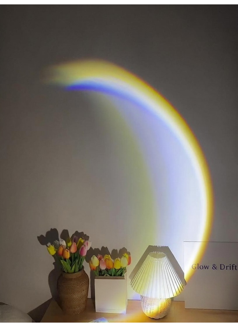 Glow & Drift Moonlight Projection Lamp casting a soft arc of light over tulips on a desk.