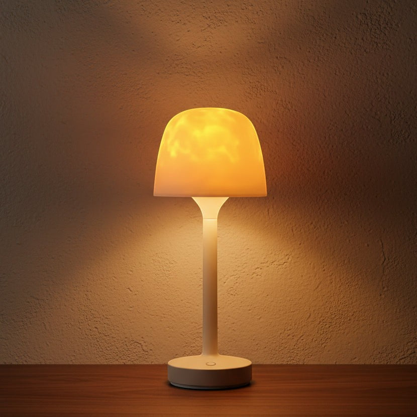Glow & Drift Ocean Aura Projector Lamp with a frosted dome emitting a warm, soft ambient light on a wooden table.