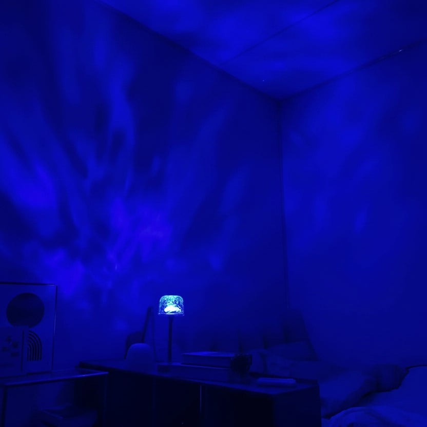 Glow & Drift Ocean Aura Projector Lamp casting vibrant blue moving water ripple light effects on a bedroom wall
