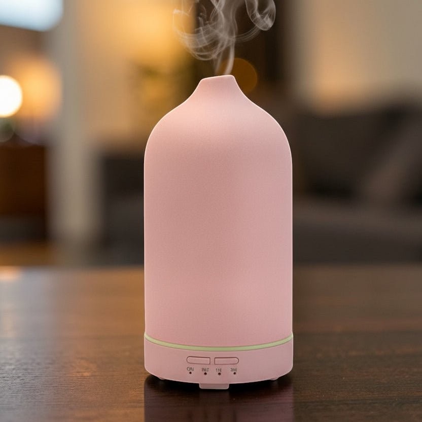 Glow & Drift minimalist frosted pink ceramic essential oil diffuser releasing a fine mist on a wooden table.