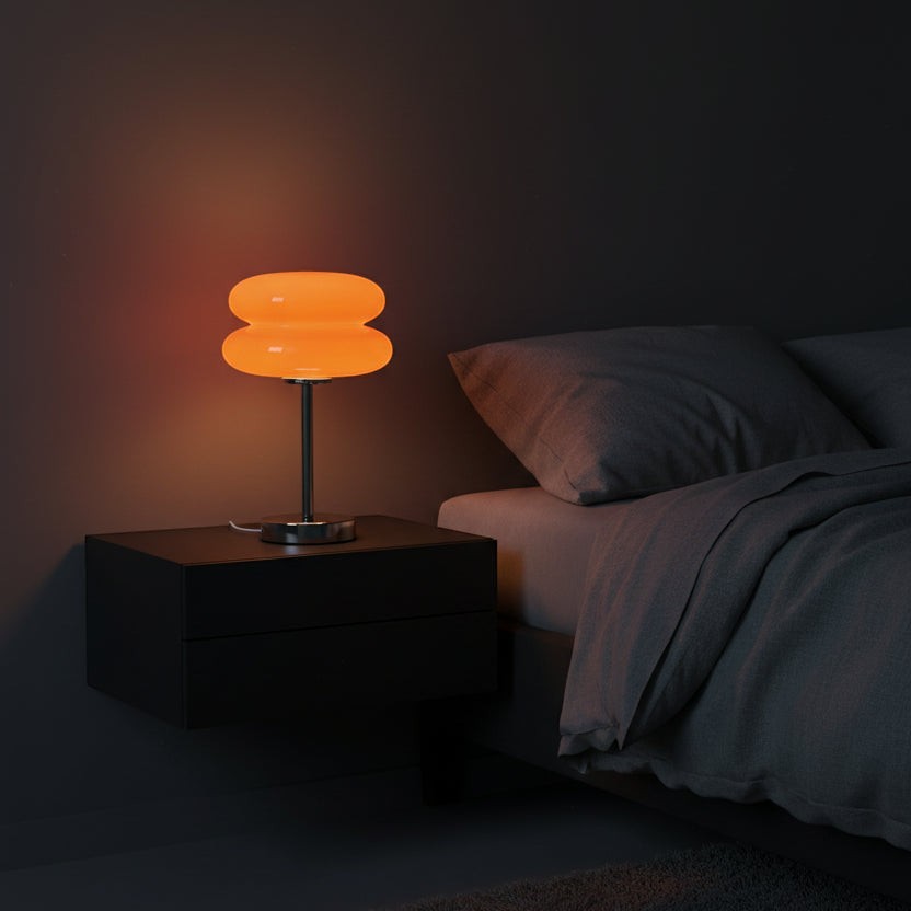 Glow & Drift retro macaron glass lamp with orange sandblasted shade on a polished steel base on a bedside table.