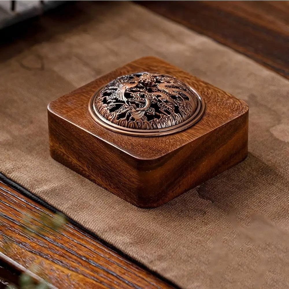 Glow & Drift square solid wood incense burner with an intricate antique-style metallic lid on a brown fabric mat