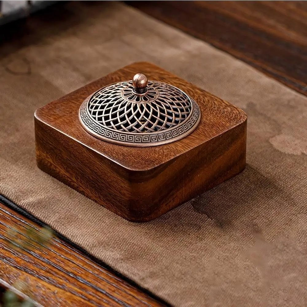Glow & Drift Heritage solid wood incense burner with an intricate antique-style metallic lid on a dark fabric surface.