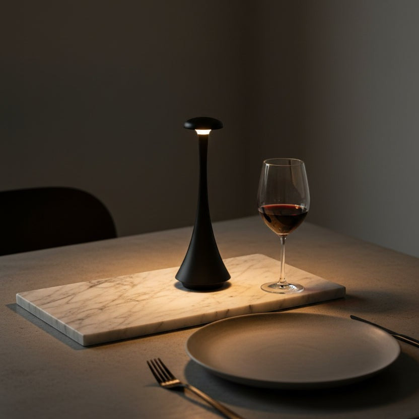 Glow & Drift Spora portable black mushroom lamp casting a warm ambient glow on a marble serving board at a dinner table