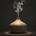 Glow & Drift Timber Wood Grain Aroma Diffuser emitting a gentle cool mist in a dark, tranquil bedroom setting.