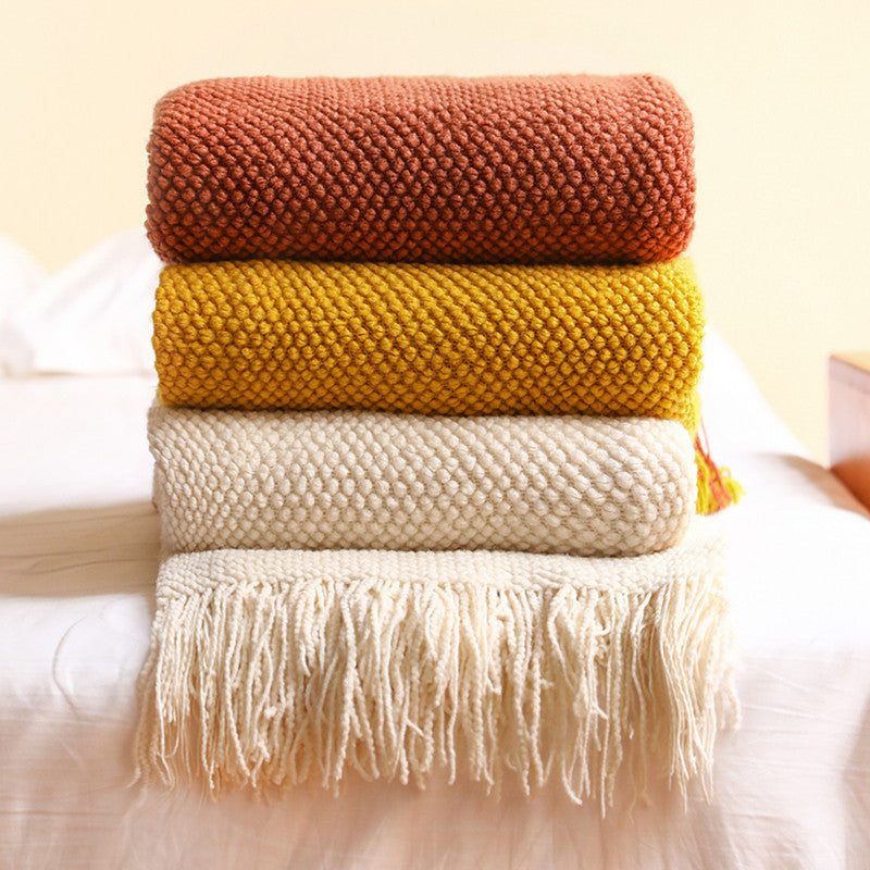 A neatly folded stack of three Waffle-Knit Sanctuary Throws by Glow & Drift in Terra Terracotta, Ochre Earth, and Chalk White, resting on a freshly made bed.