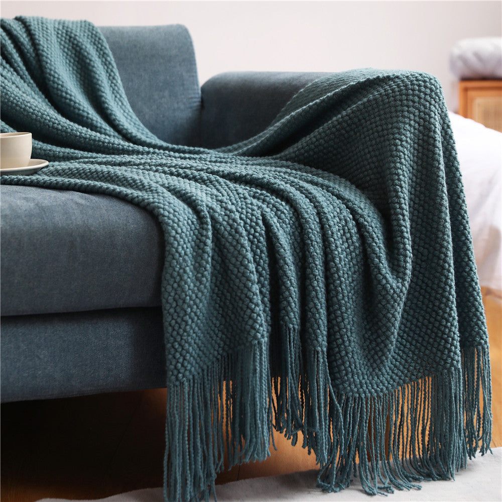 The Waffle-Knit Sanctuary Throw by Glow & Drift in Deep Indigo, draped beautifully across a blue armchair to create a cozy, calming reading space.