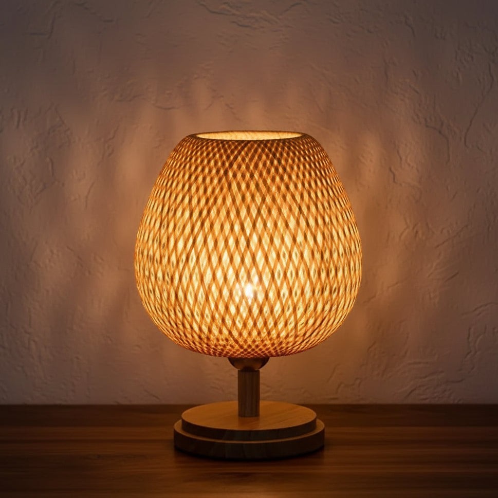 Glow & Drift globe-shaped bamboo table lamp with intricate woven rattan shade casting warm geometric light patterns