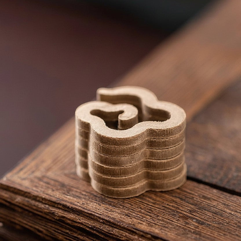 Glow & Drift Xiangyun cloud-shaped natural incense stack on a dark wooden surface for meditation and relaxation.
