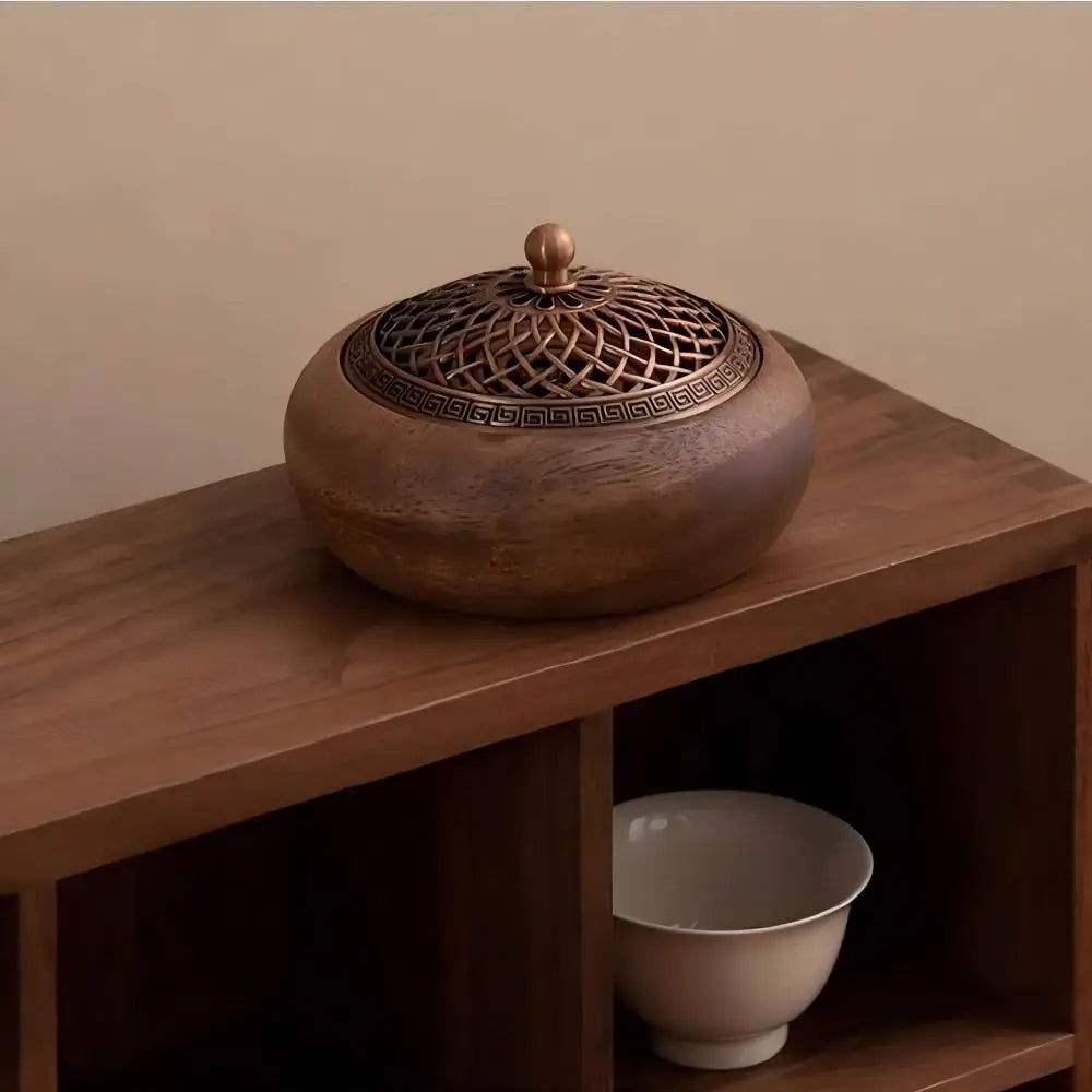 Zen room decor showing the closed round wood incense burner styled beautifully on a wooden shelf unit next to a white ceramic tea cup.