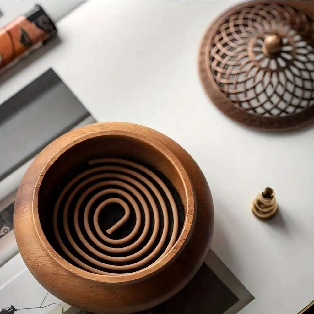 A top-down aesthetic shot of a sandalwood incense coil resting inside the Heritage round wood burner base with its geometric brass lid nearby.