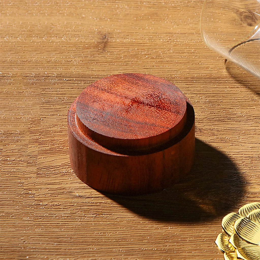 A close-up macro shot showing the premium dark wood circular base component of The Hourglass Waterfall Incense Vessel resting on a textured wooden tabletop