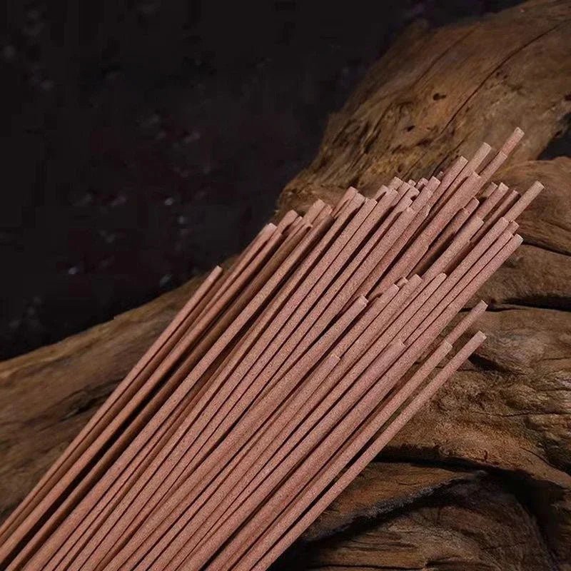 Close-up texture shot of loose, high-quality wooden incense sticks on a rustic wood surface.