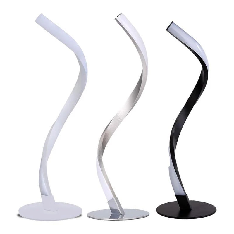 Three serpentine LED table lamps lined up showcasing the alabaster white, brushed chrome, and matte black finish options.